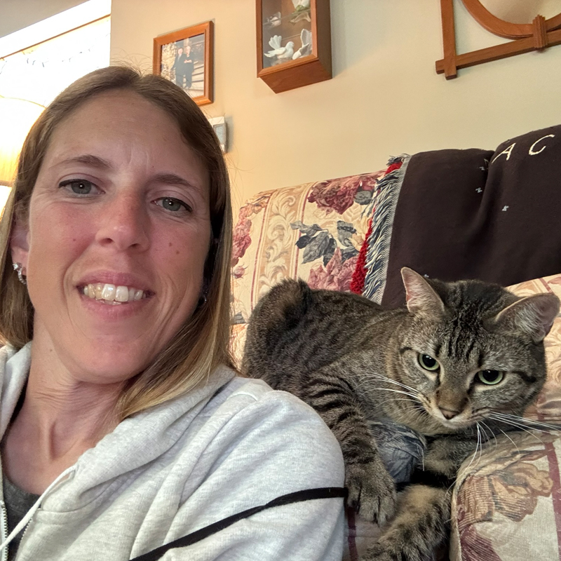 Regina playing with a cat on the couch while doing a drop-in visit